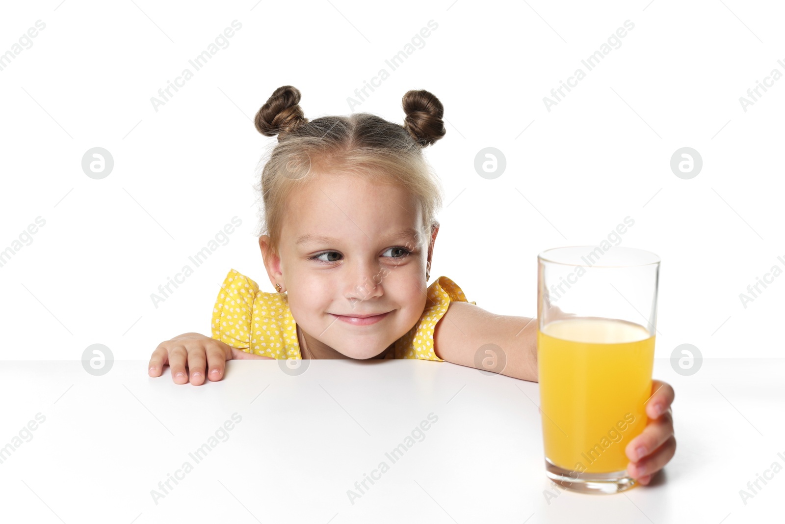 Cute little girl reaching for glass of orange juice at table against white background Photo of Cute little girl reaching for glass of orange juice at table against white background