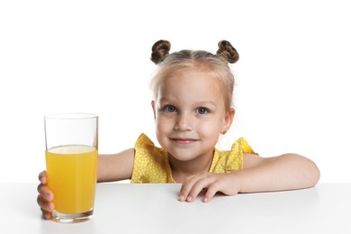 Photo of Cute little girl reaching for glass of orange juice at table against white background