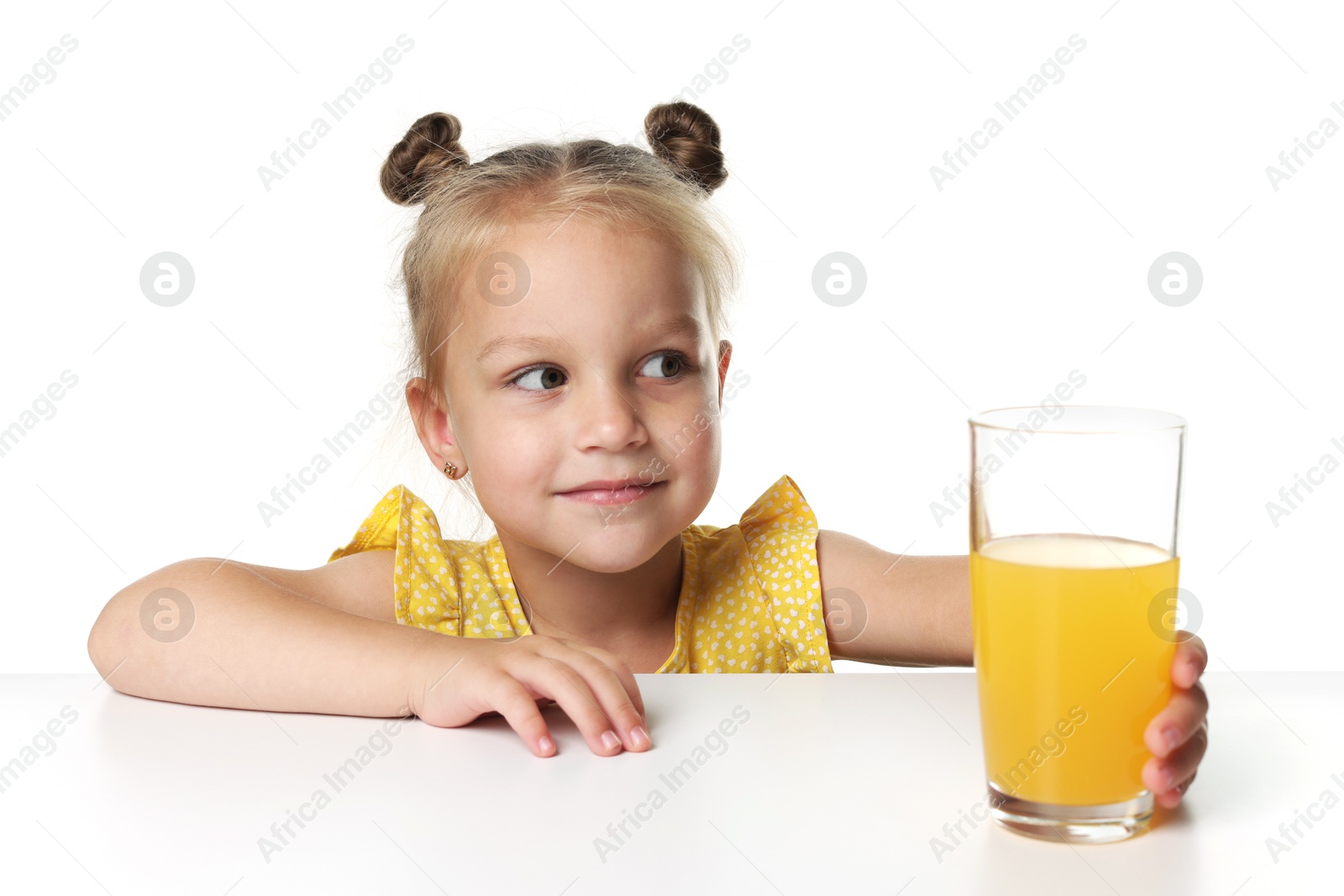 Cute little girl reaching for glass of orange juice at table against white background Photo of Cute little girl reaching for glass of orange juice at table against white background