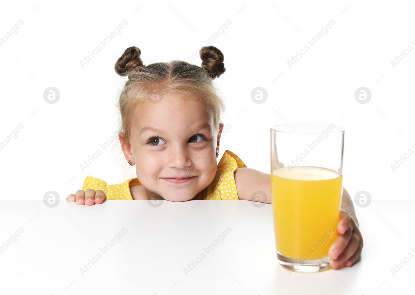 Cute little girl reaching for glass of orange juice at table against white background Photo of Cute little girl reaching for glass of orange juice at table against white background