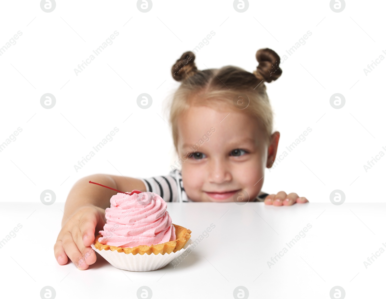 Cute little girl reaching for tasty dessert at table against white background, selective focus Photo of Cute little girl reaching for tasty dessert at table against white background, selective focus