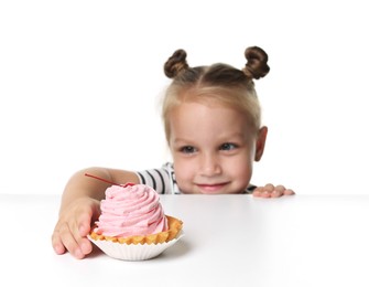 Photo of Cute little girl reaching for tasty dessert at table against white background, selective focus