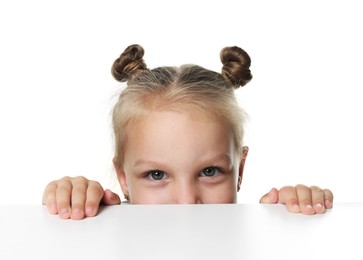Photo of Curious little girl peeking over table against white background
