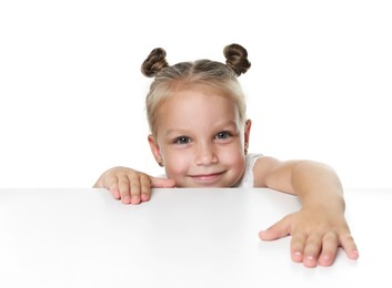 Photo of Curious little girl peeking over table against white background