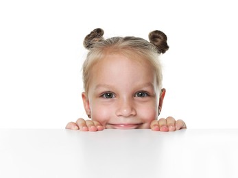 Photo of Curious little girl peeking over table against white background