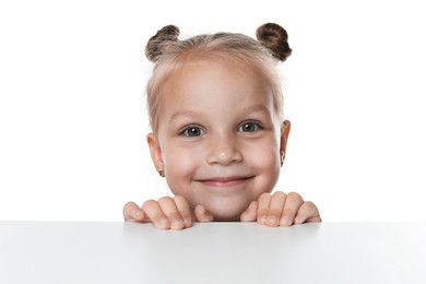 Photo of Curious little girl peeking over table against white background