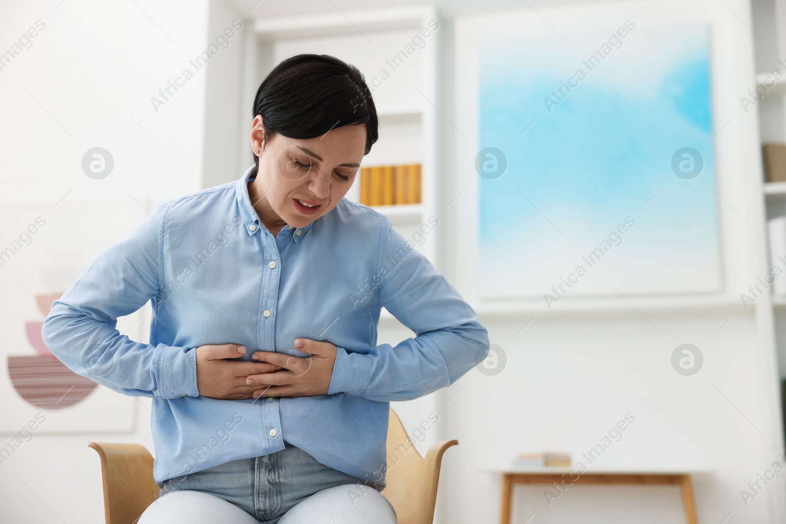 Woman suffering from stomachache at home. Space for text Photo of Woman suffering from stomachache at home. Space for text