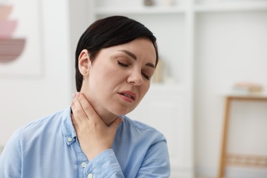Photo of Woman suffering from sore throat at home. Space for text