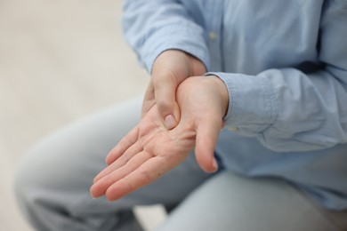 Photo of Woman suffering from hand pain at home, closeup