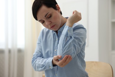 Photo of Woman suffering from elbow pain at home