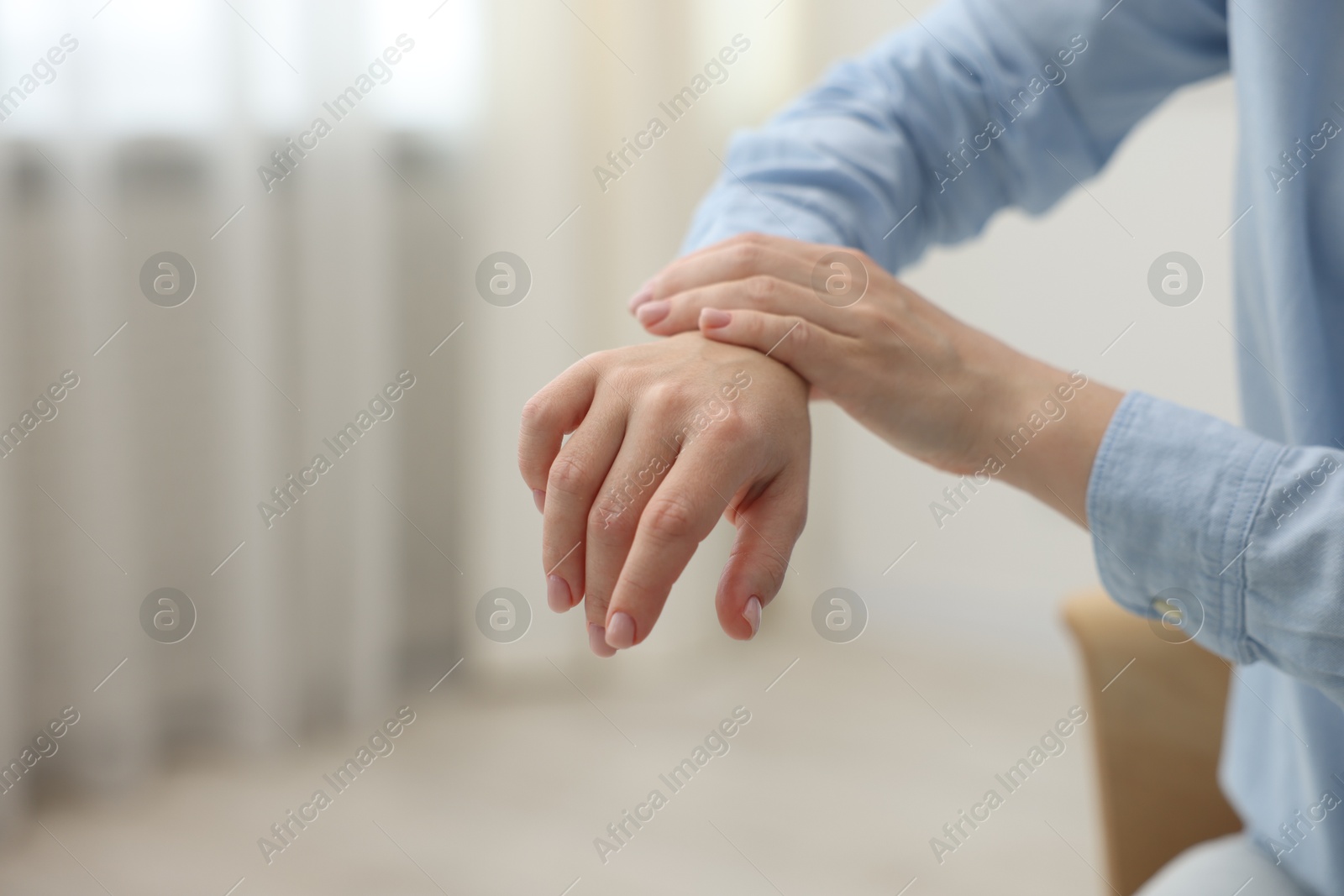 Photo of Woman suffering from wrist pain at home, closeup. Space for text
