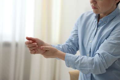 Photo of Woman suffering from wrist pain at home, closeup