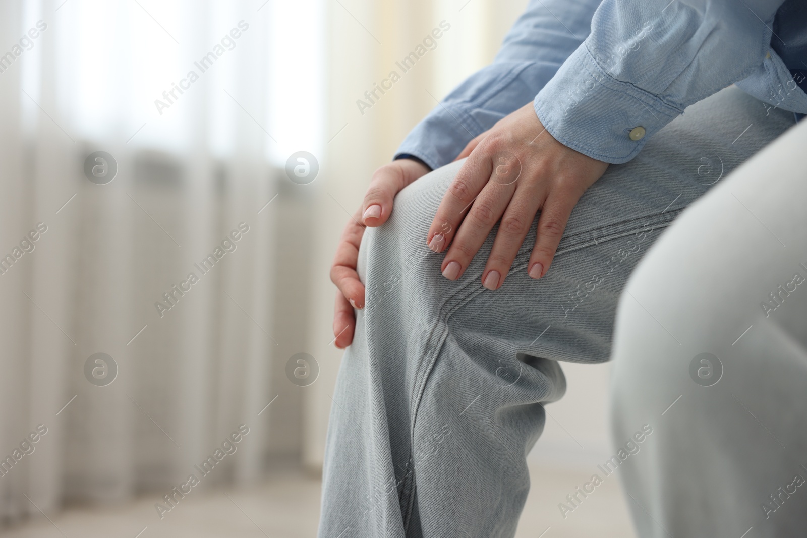 Photo of Woman suffering from knee pain at home, closeup. Space for text