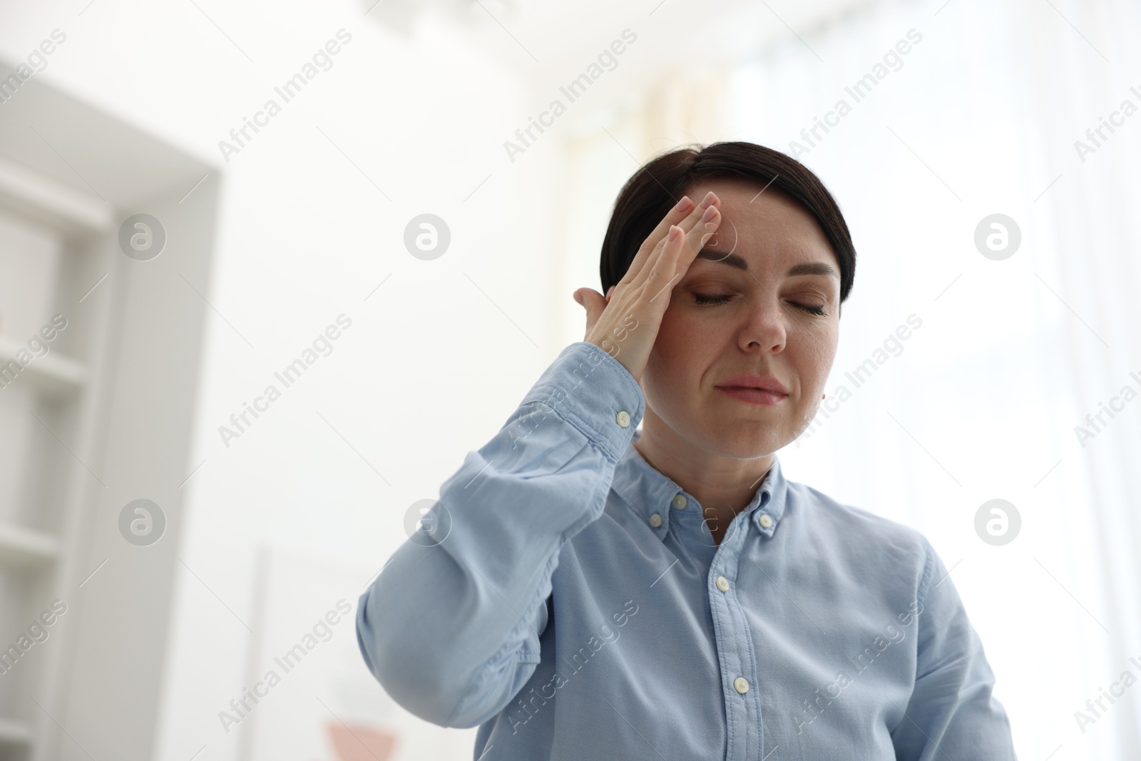 Photo of Woman suffering from headache at home, low angle view. Space for text
