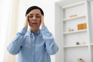 Photo of Woman suffering from headache at home, low angle view. Space for text