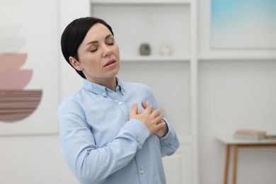 Photo of Woman suffering from chest pain at home. Space for text
