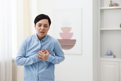 Photo of Woman suffering from chest pain at home. Space for text