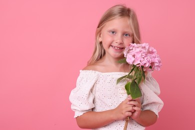 Photo of Portrait of smiling little girl with hydrangea flowers on pink background. Space for text