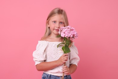 Photo of Portrait of cute little girl with hydrangea flowers on pink background