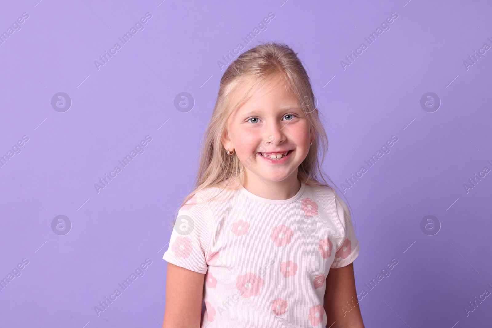 Photo of Smiling little girl on violet background. Positive emotion