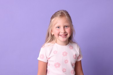 Photo of Smiling little girl on violet background. Positive emotion