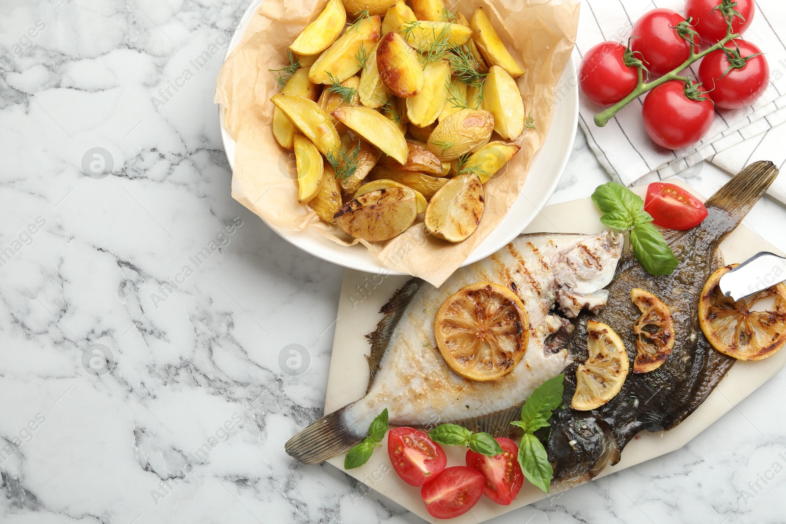Photo of Homemade seafood dish. Tasty roasted flounder fish served with potatoes, tomatoes, basil and lemon slices on white marble table, flat lay. Space for text