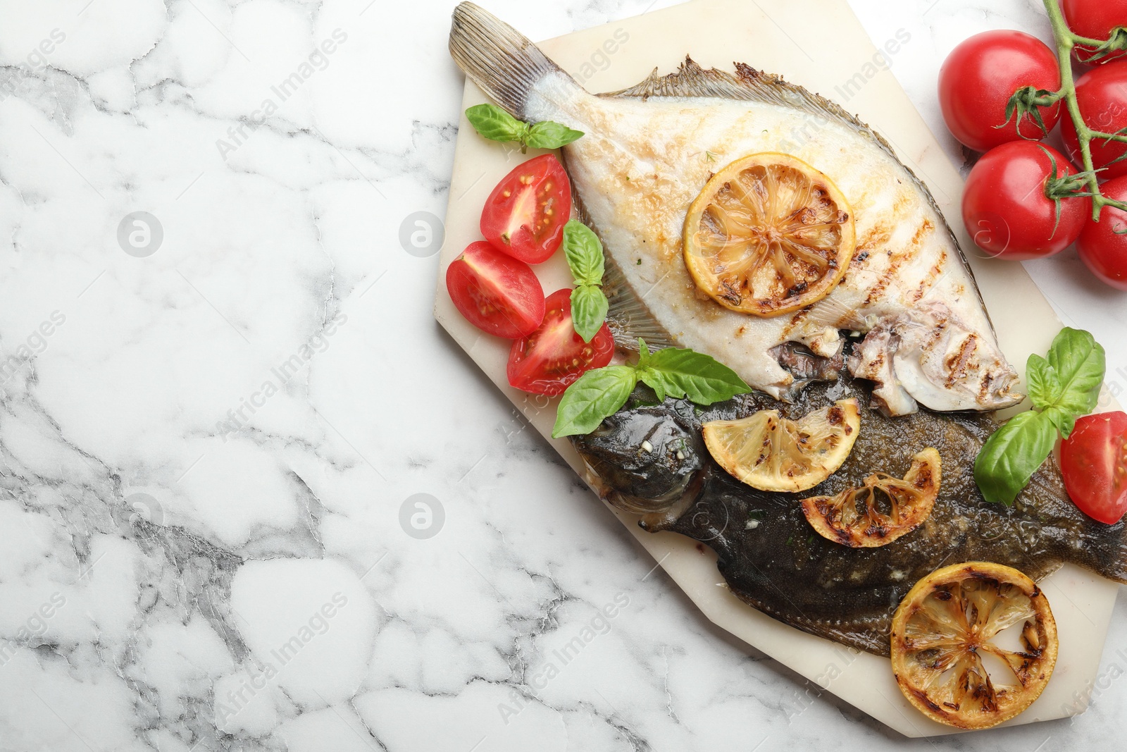 Photo of Homemade seafood dish. Tasty roasted flounder fish served with tomatoes, basil and lemon slices on white marble table, flat lay. Space for text
