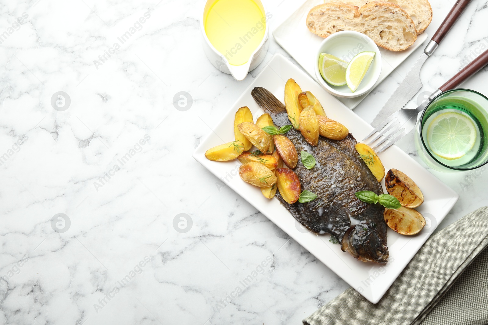 Photo of Homemade seafood dish. Tasty roasted flounder fish served with potatoes, basil and lemon slices on white marble table, flat lay. Space for text