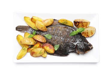 Photo of Tasty roasted flounder fish with potatoes, basil and lemon slices isolated on white, top view. Homemade seafood dish