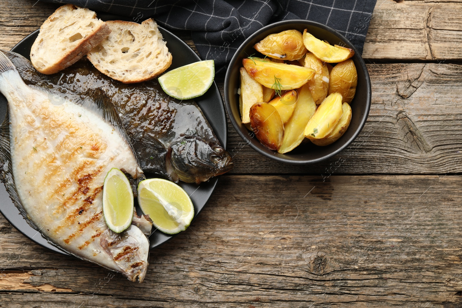 Photo of Homemade seafood dish. Tasty roasted flounder fish served with potatoes, bread and lime slices on wooden table, flat lay. Space for text