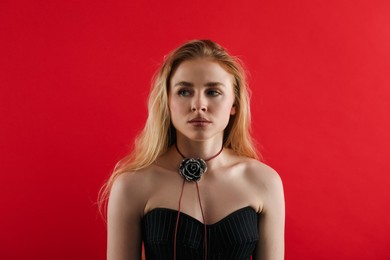 Photo of Beautiful woman in stylish necklace on red background