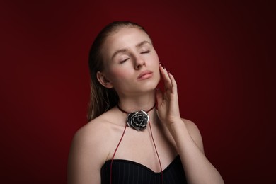 Photo of Beautiful woman in stylish necklace posing on dark red background