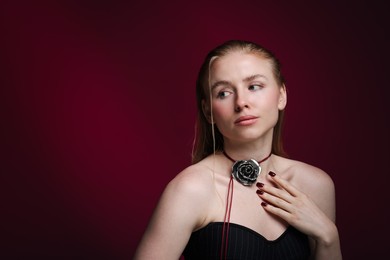 Photo of Beautiful woman in stylish necklace posing on dark red background. Space for text