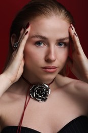 Photo of Fashionable portrait of beautiful woman in stylish necklace and ring posing on dark red background, closeup
