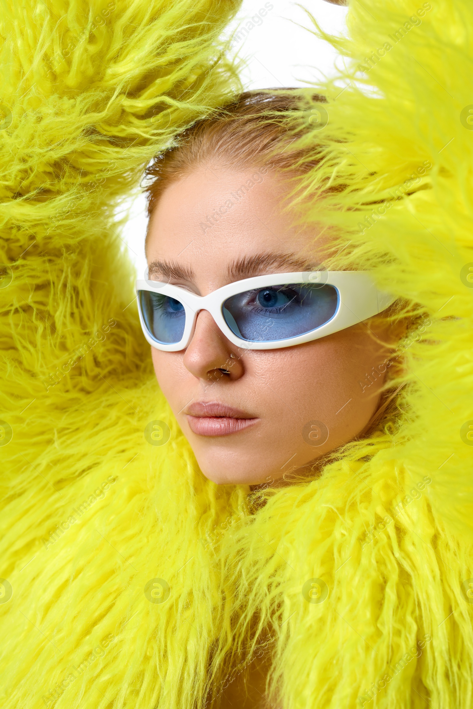 Photo of Beautiful woman in stylish sunglasses and fur coat posing on white background, closeup