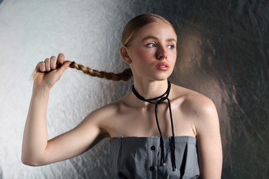 Photo of Beautiful woman with pigtail posing on metallic background