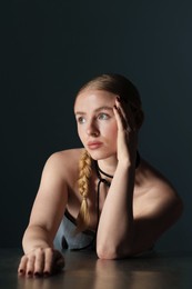 Photo of Beautiful woman with pigtail posing at table on dark background