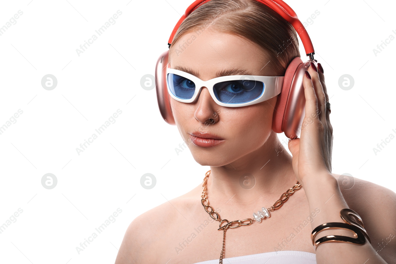 Photo of Fashionable portrait of beautiful woman in stylish sunglasses, bijouterie and headphones listening to music on white background