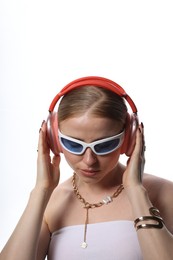 Photo of Beautiful woman in stylish sunglasses, bijouterie and headphones listening to music on white background