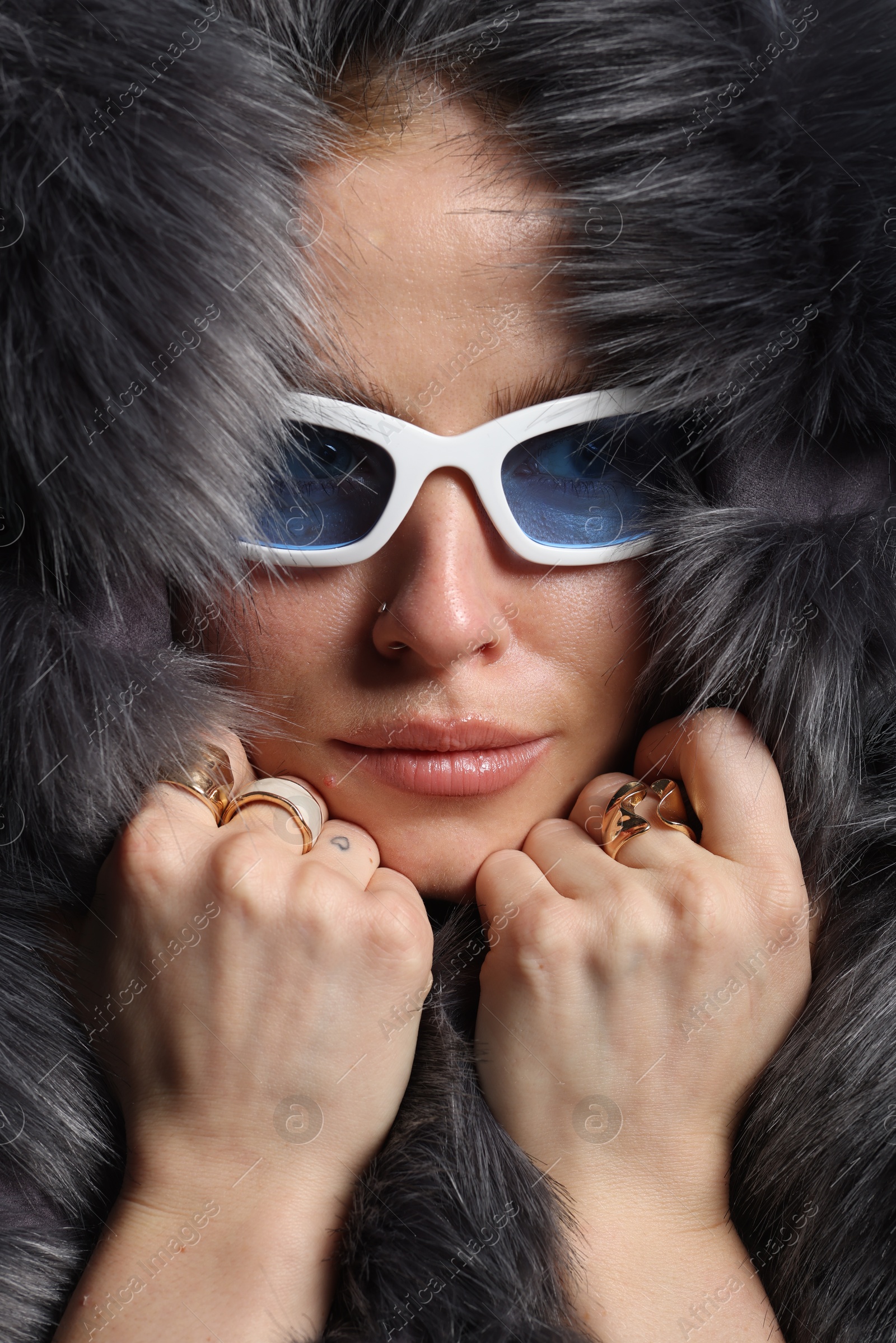 Photo of Fashionable portrait of beautiful woman in stylish sunglasses, rings and fur coat, closeup