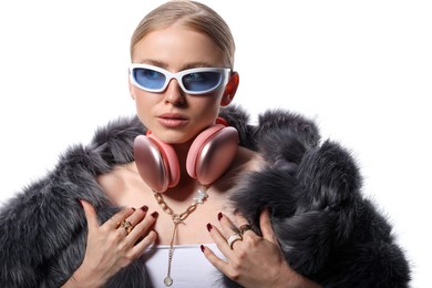 Photo of Beautiful woman in stylish sunglasses, bijouterie, fur coat and headphones on white background