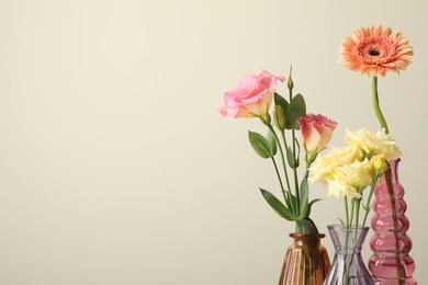 Photo of Different beautiful flowers in glass vases on light grey background, closeup. Space for text