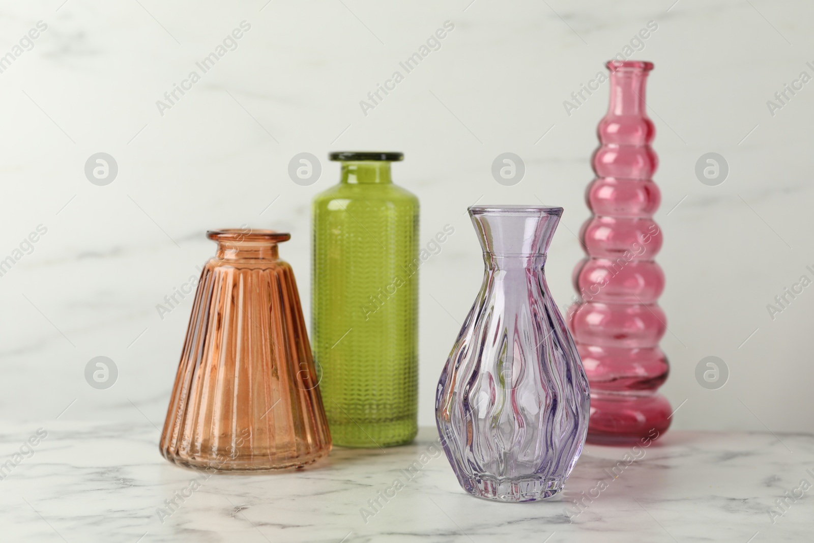 Photo of Different beautiful glass vases on white marble table