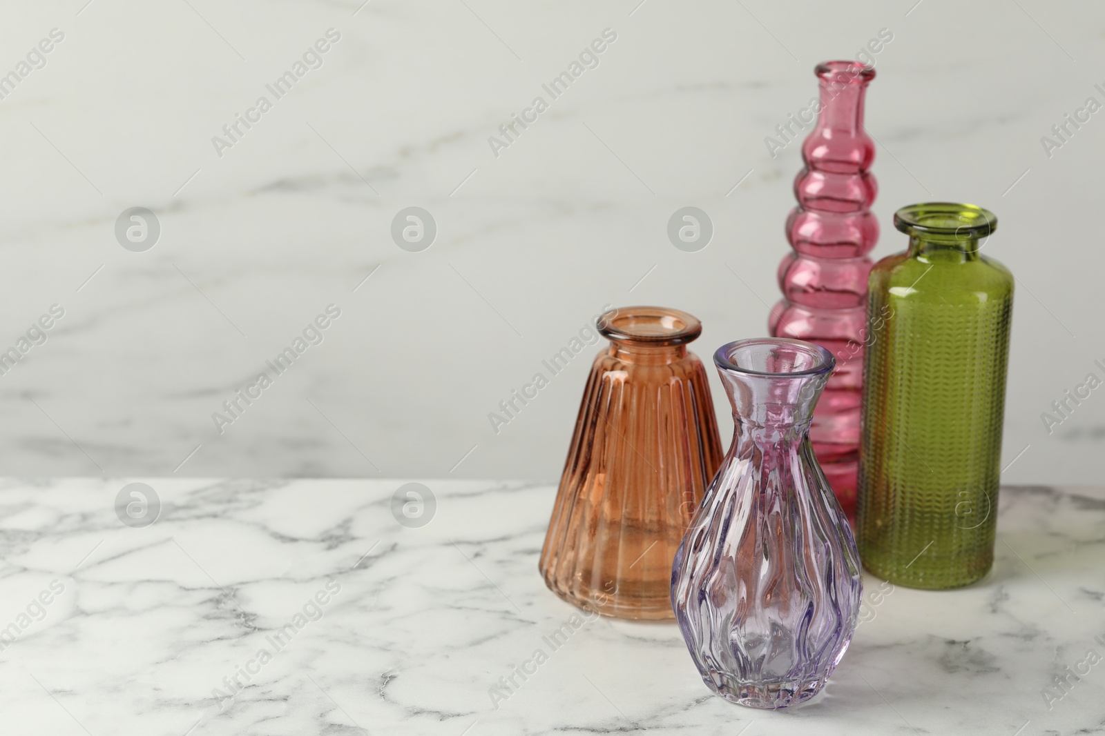 Photo of Different beautiful glass vases on white marble table, space for text