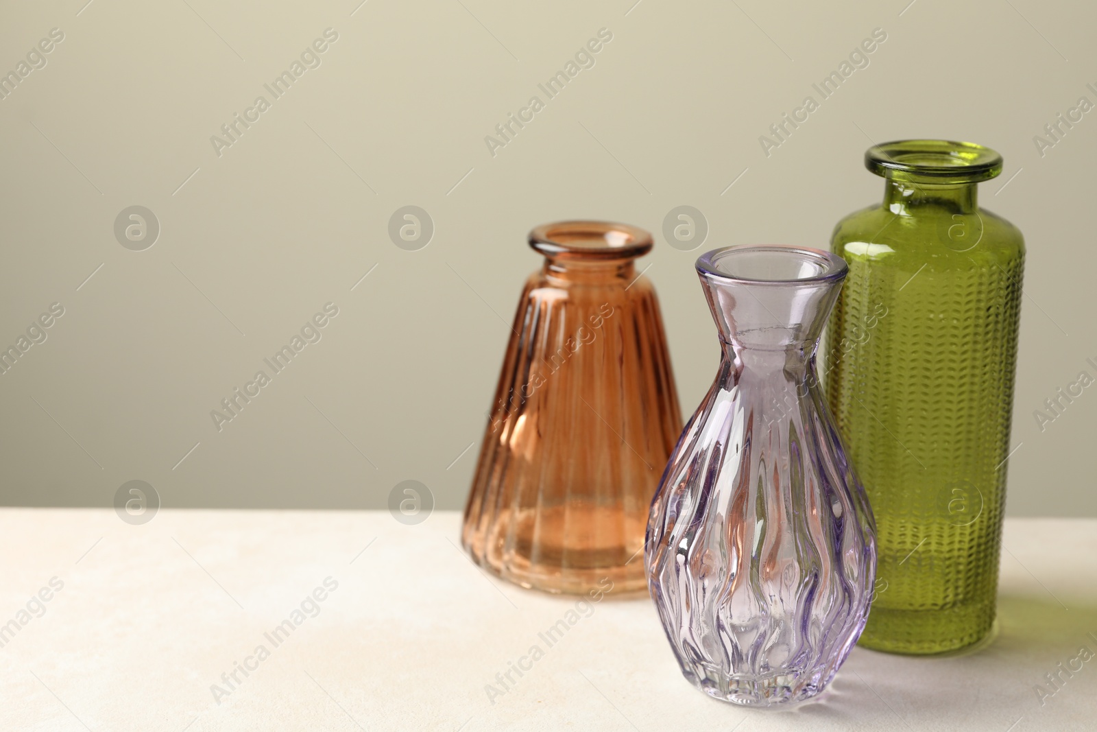 Different beautiful glass vases on white table against light grey background, closeup. Space for text Photo of Different beautiful glass vases on white table against light grey background, closeup. Space for text