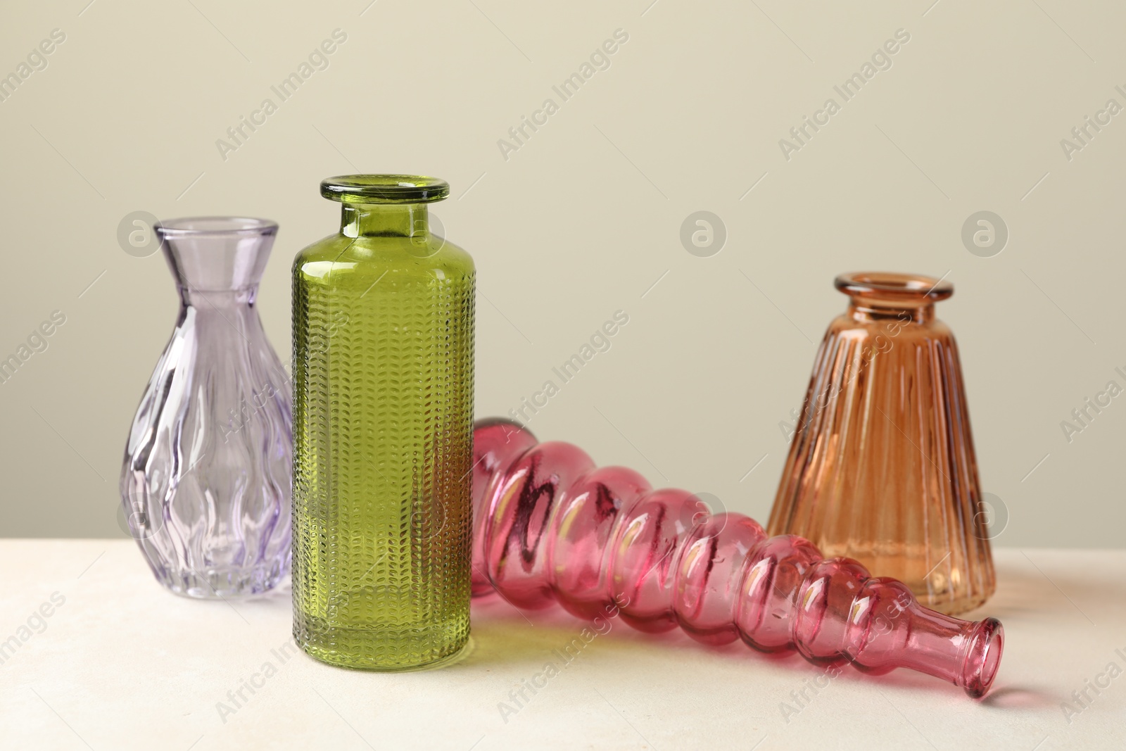 Different beautiful glass vases on white table against light grey background Photo of Different beautiful glass vases on white table against light grey background