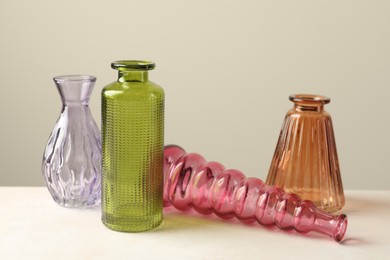 Photo of Different beautiful glass vases on white table against light grey background