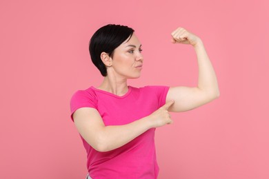 Photo of Strength. Beautiful woman showing her biceps on pink background