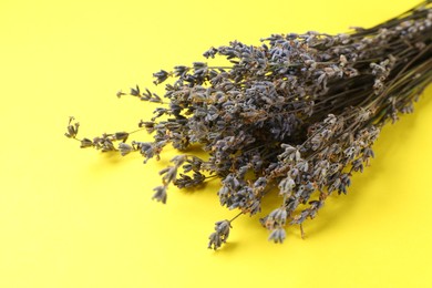 Photo of Bunch of fragrant lavender flowers on yellow background, closeup