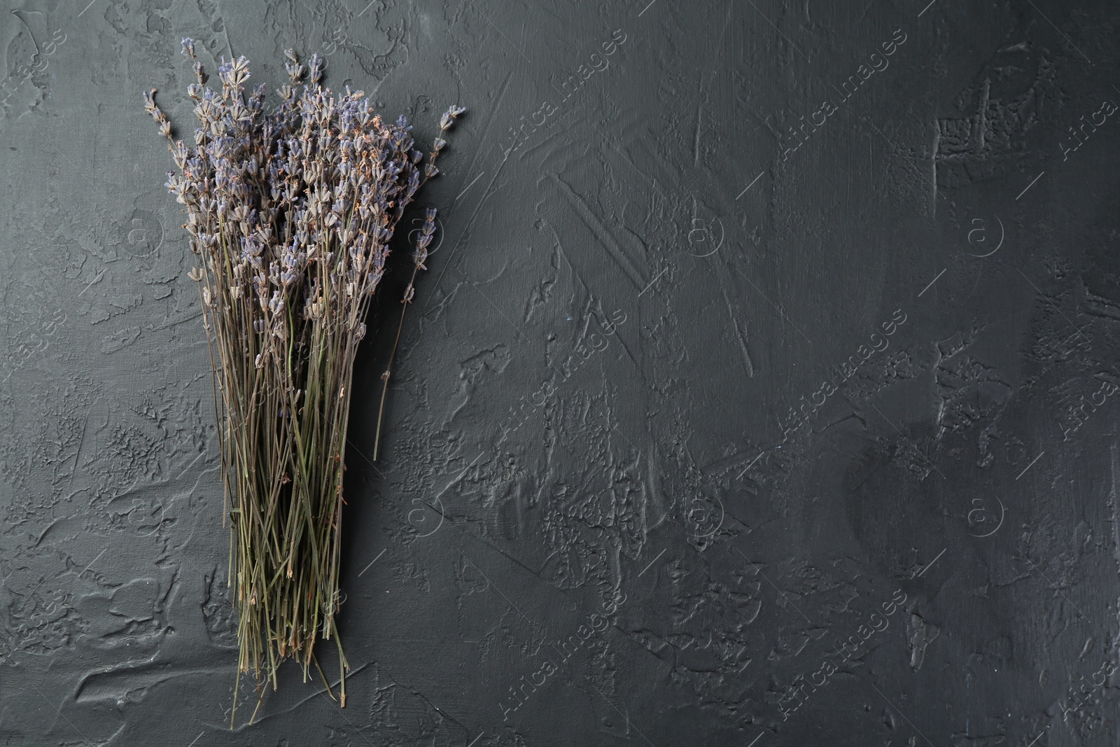 Photo of Bunch of fragrant lavender flowers on black textured table, top view. Space for text